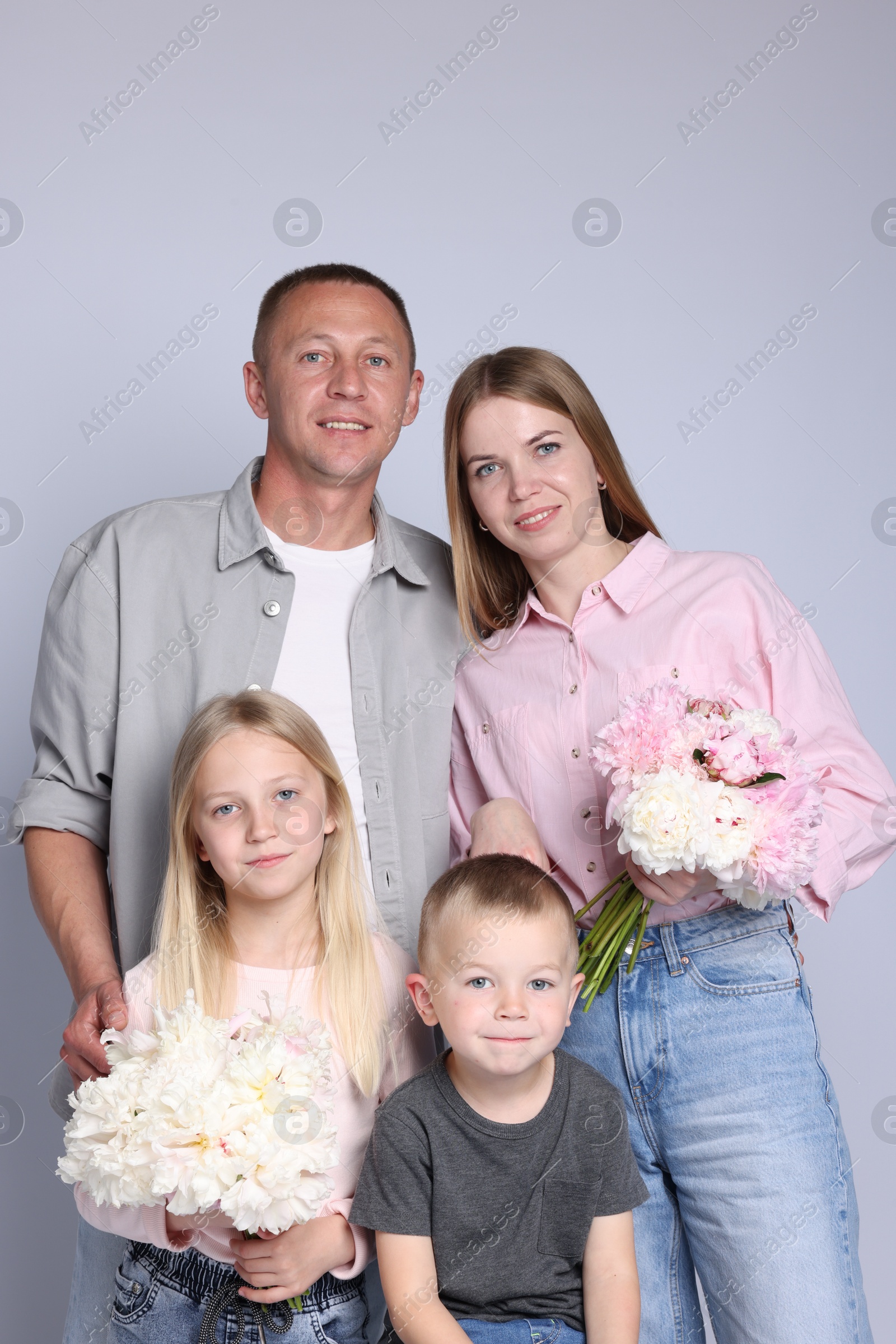 Family portrait of happy parents and their children with flowers on grey background Photo of Family portrait of happy parents and their children with flowers on grey background