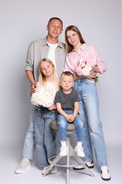 Photo of Full length portrait of happy family with flowers on grey background