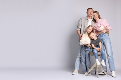 Photo of Full length portrait of happy family with flowers on grey background. Space for text