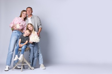 Photo of Full length portrait of happy family with flowers on grey background. Space for text