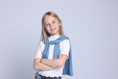 Photo of Portrait of smiling girl with crossed arms on grey background