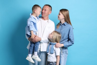 Photo of Cute family looking at each other on light blue background