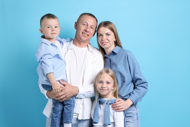 Photo of Family portrait of happy parents and their children on light blue background