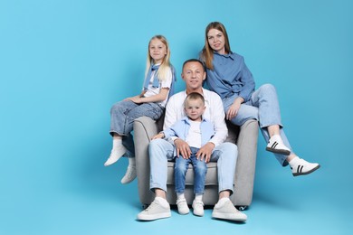 Photo of Happy family sitting on armchair against light blue background