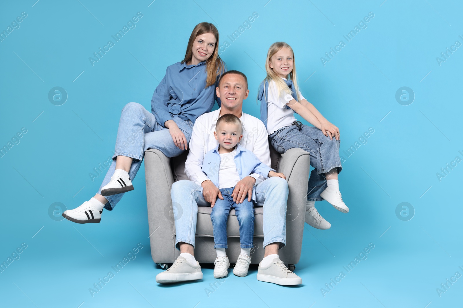 Photo of Happy family sitting on armchair against light blue background