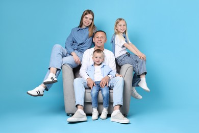 Photo of Happy family sitting on armchair against light blue background