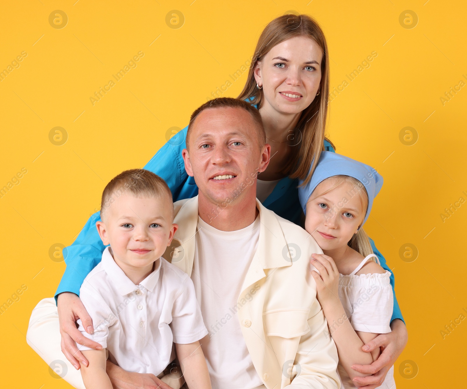 Family portrait of happy parents and their children on yellow background Photo of Family portrait of happy parents and their children on yellow background