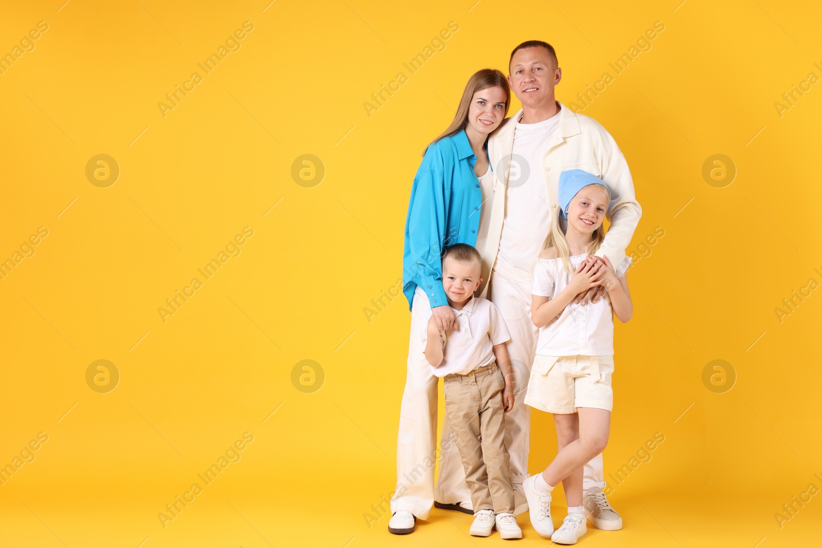 Photo of Full length portrait of happy family on yellow background. Space for text