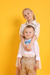 Photo of Cute brother and sister posing on yellow background