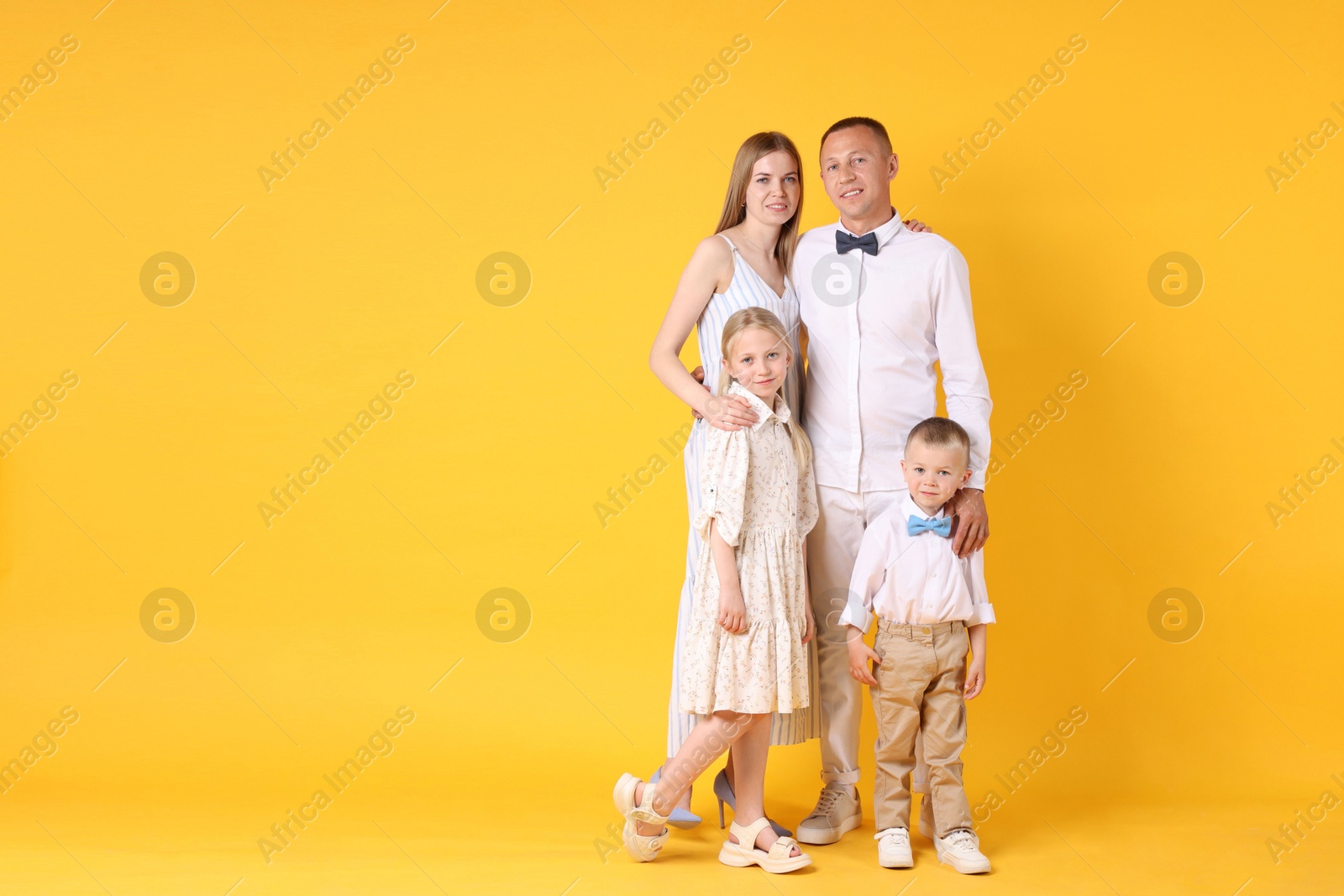 Full length portrait of happy family on yellow background. Space for text Photo of Full length portrait of happy family on yellow background. Space for text