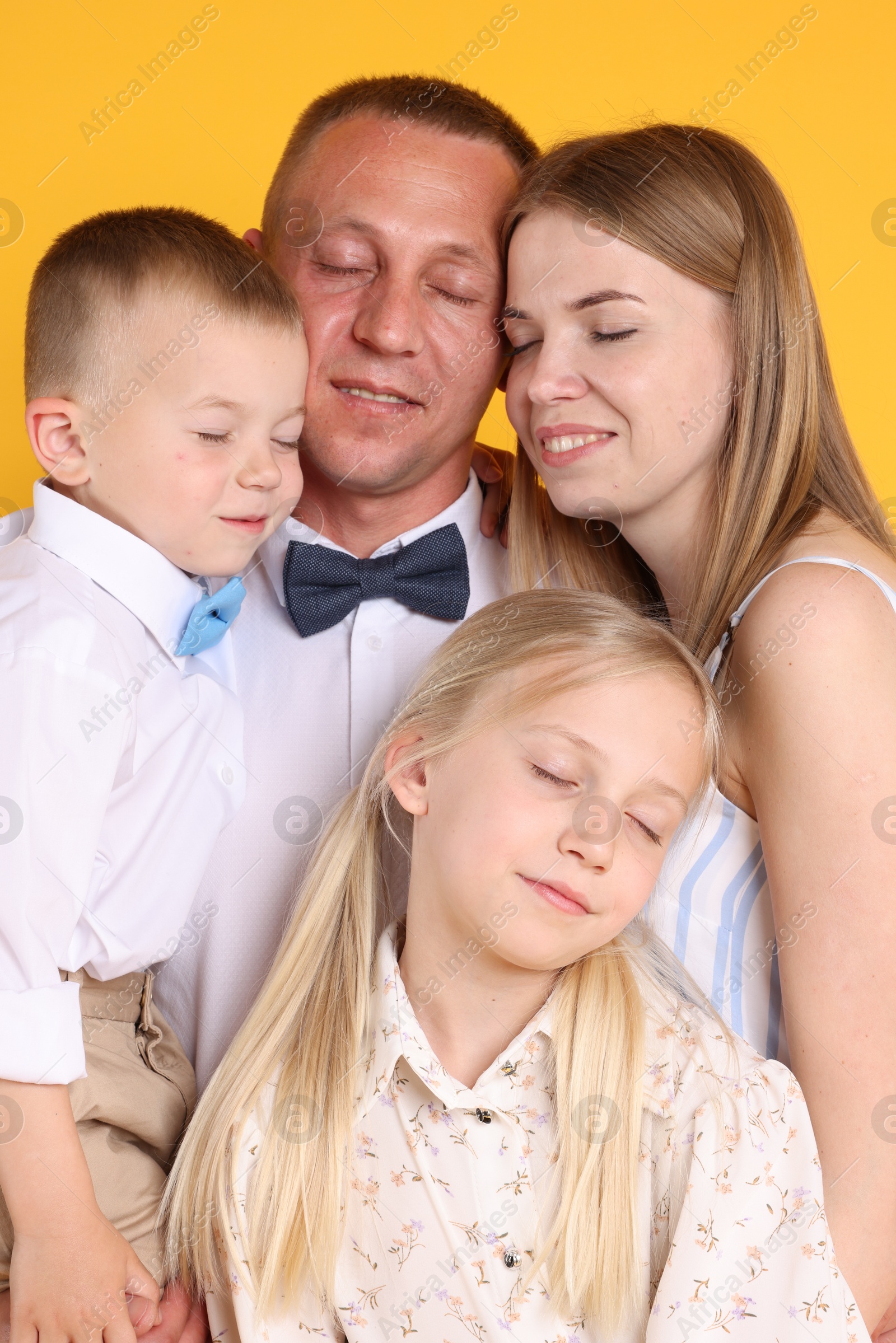 Cute family with closed eyes posing on yellow background Photo of Cute family with closed eyes posing on yellow background