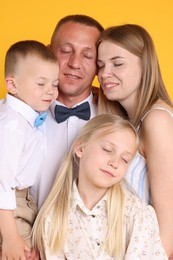 Photo of Cute family with closed eyes posing on yellow background