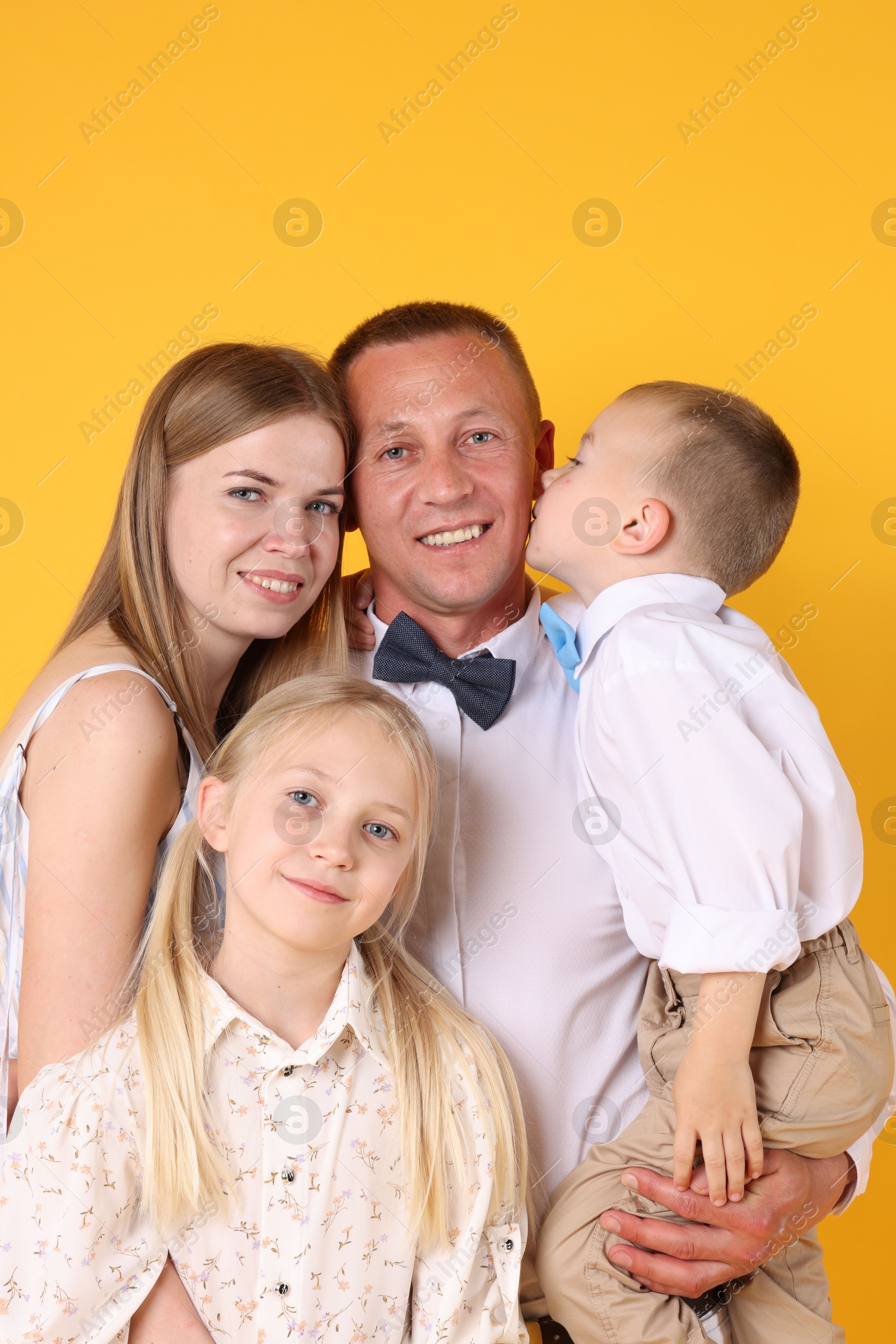 Family portrait of happy parents and their children on yellow background Photo of Family portrait of happy parents and their children on yellow background