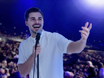 Image of Man singing on stage of concert hall crowded with people