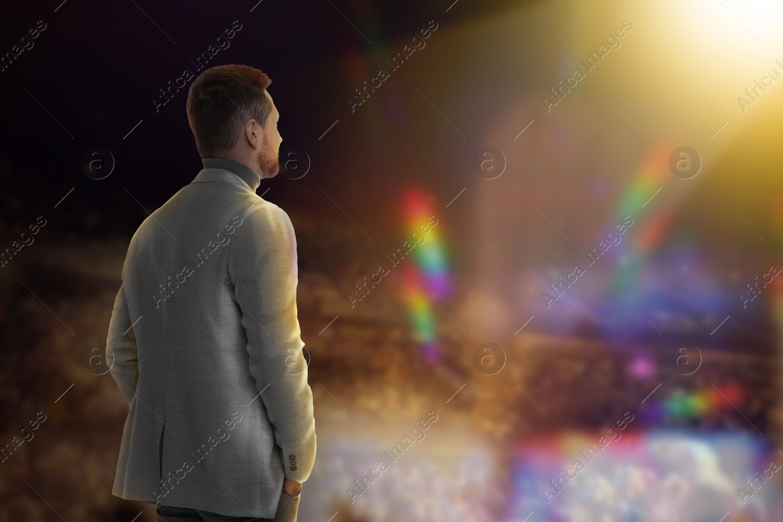 Image of Man performing on stage of concert hall crowded with people