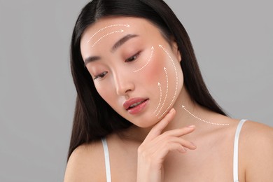 Image of Beautiful woman with perfect skin after collagen treatment on grey background. Arrows on her face illustrating lifting and smoothing effect