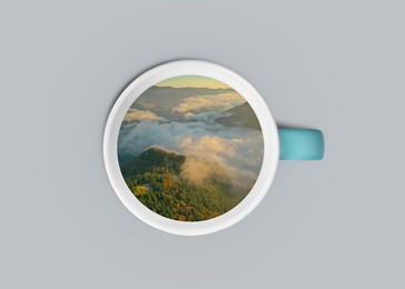 Image of Mountain landscape on sunny morning in cup on grey background, top view