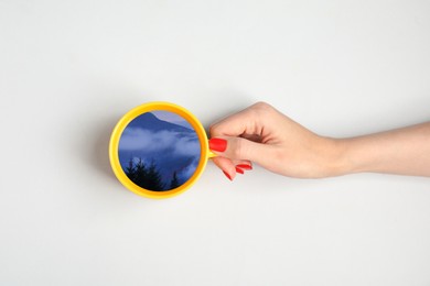 Image of Woman holding cup with mountain landscape inside on white background, top view
