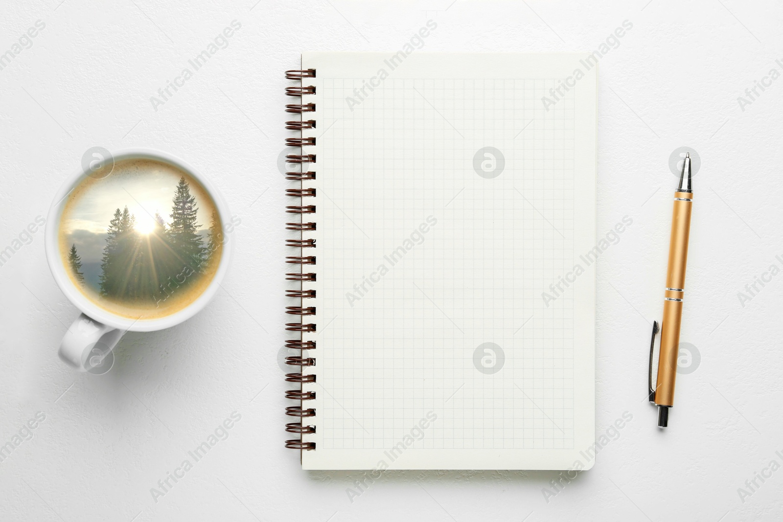 Cup with mountain landscape on sunny morning inside. Empty notebook, pen and cup on white table, top view Image of Cup with mountain landscape on sunny morning inside. Empty notebook, pen and cup on white table, top view