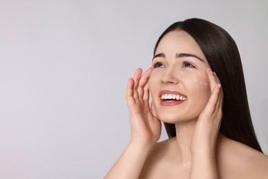 Image of Beautiful woman with perfect skin after collagen treatment on grey background, space for text. Arrows on her face illustrating lifting and smoothing effect