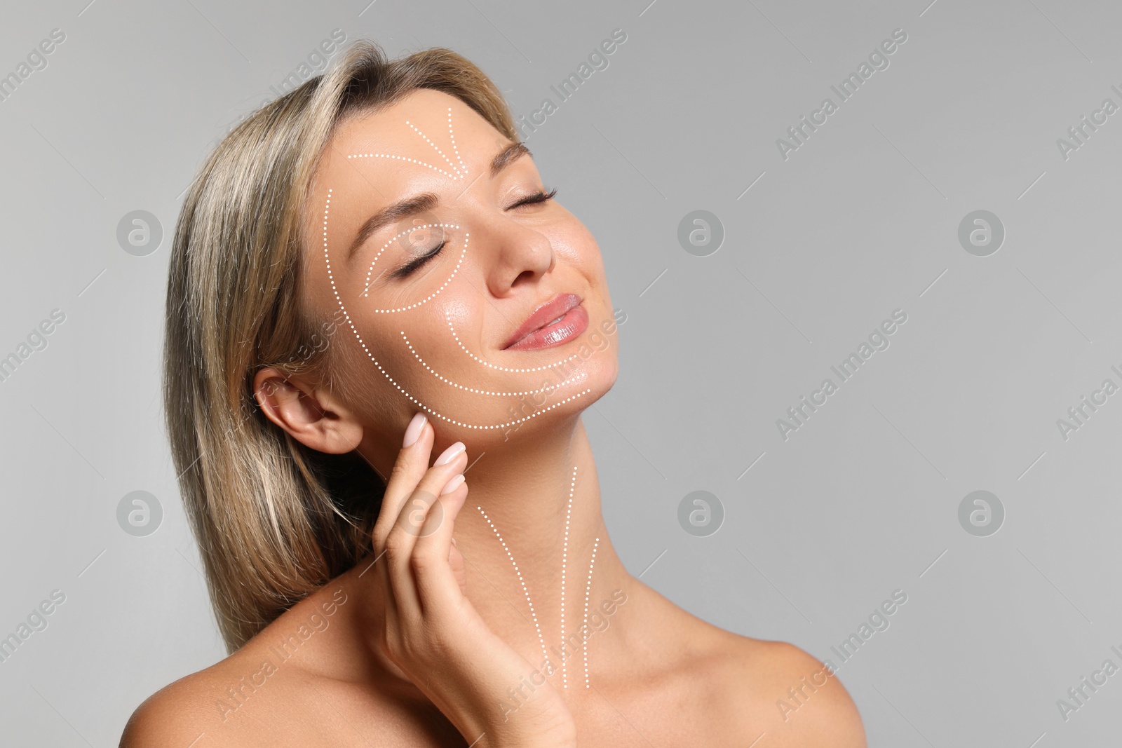 Beautiful woman with perfect skin after collagen treatment on grey background, space for text. Lines on her face illustrating lifting and smoothing effect Image of Beautiful woman with perfect skin after collagen treatment on grey background, space for text. Lines on her face illustrating lifting and smoothing effect