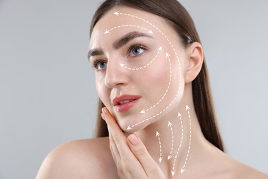 Image of Beautiful woman with perfect skin after collagen treatment on grey background. Arrows on her face illustrating lifting and smoothing effect