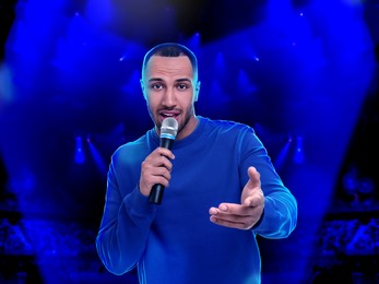Image of Man singing on stage of concert hall crowded with people