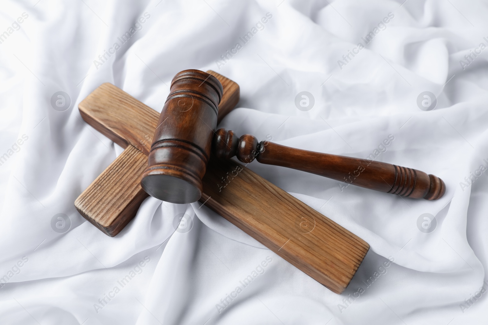 Judge's gavel and wooden cross on white fabric, above view Photo of Judge's gavel and wooden cross on white fabric, above view