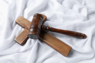 Photo of Judge's gavel and wooden cross on white fabric, above view
