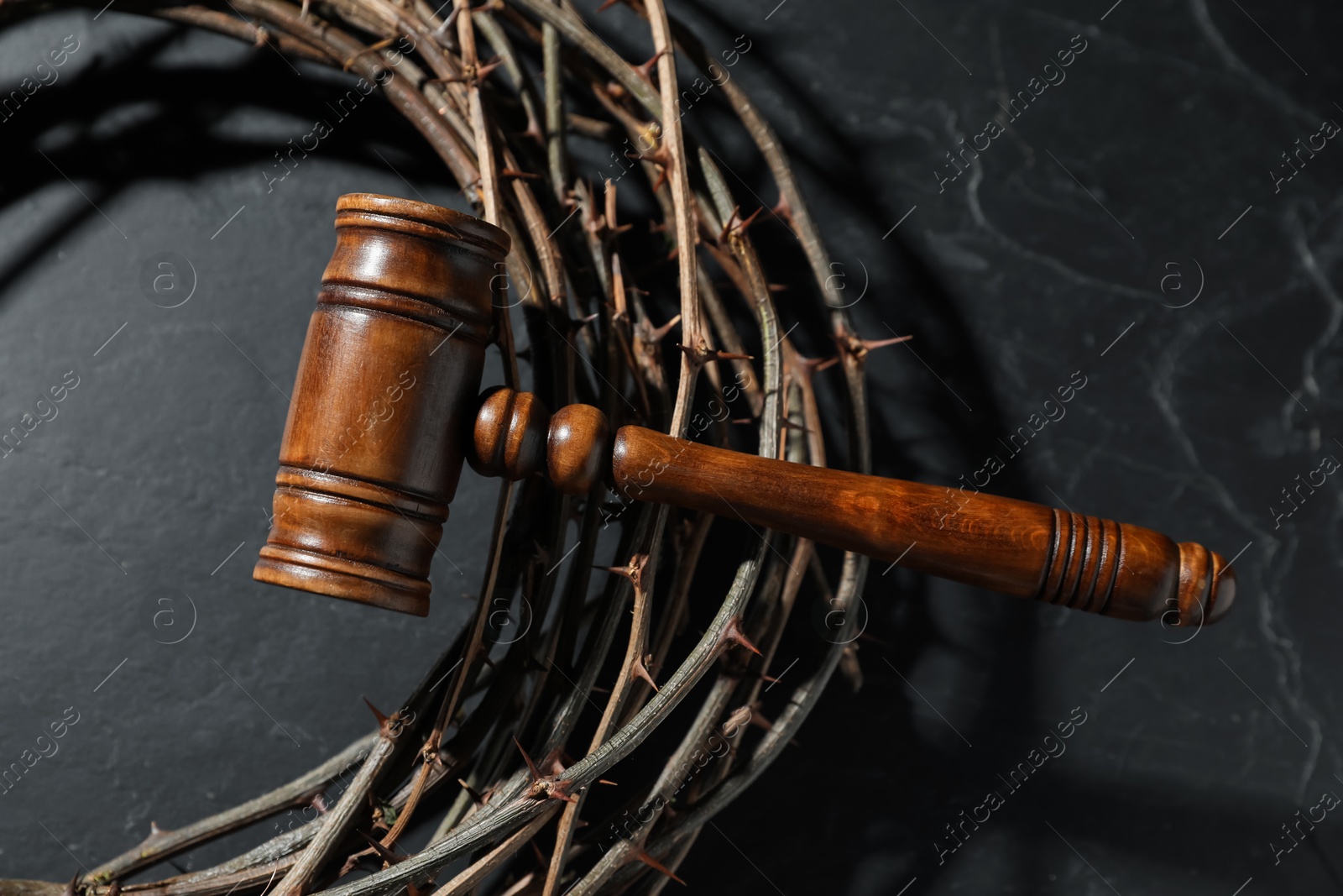 Judge's gavel and crown of thorns on black table, top view Photo of Judge's gavel and crown of thorns on black table, top view
