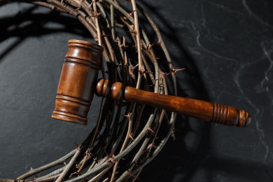 Photo of Judge's gavel and crown of thorns on black table, top view