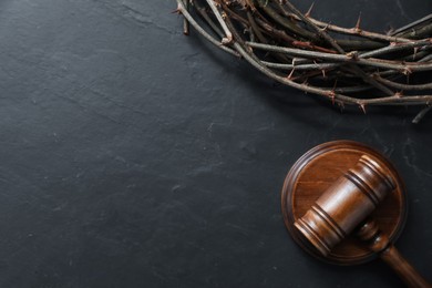 Photo of Judge's gavel and crown of thorns on black table, flat lay. Space for text