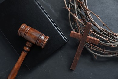 Photo of Judge's gavel, crown of thorns, Bible and wooden cross on black table, flat lay