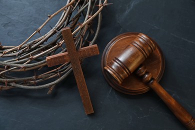 Photo of Judge's gavel, crown of thorns and wooden cross on black table, flat lay