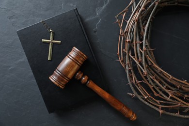 Photo of Judge's gavel, crown of thorns, Bible and cross on black table, flat lay