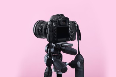 Photo of Modern professional video camera on pink background, closeup