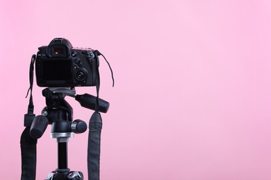 Photo of Modern professional video camera on pink background, space for text