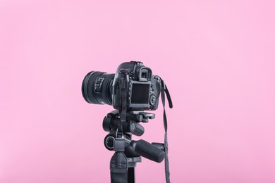 Photo of Modern professional video camera on pink background