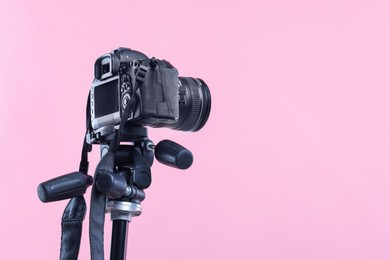 Photo of Modern professional video camera on pink background, low angle view. Space for text