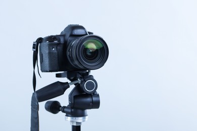 Photo of Modern professional video camera on light grey background, closeup. Space for text