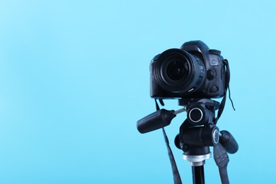 Photo of Professional video camera on light blue background, space for text