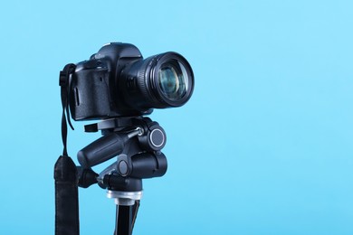 Photo of Professional video camera on light blue background, space for text