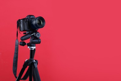 Photo of Modern professional video camera on red background, space for text