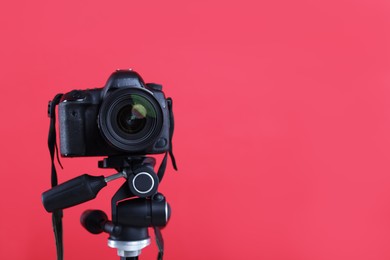 Photo of Modern professional video camera on red background, closeup. Space for text