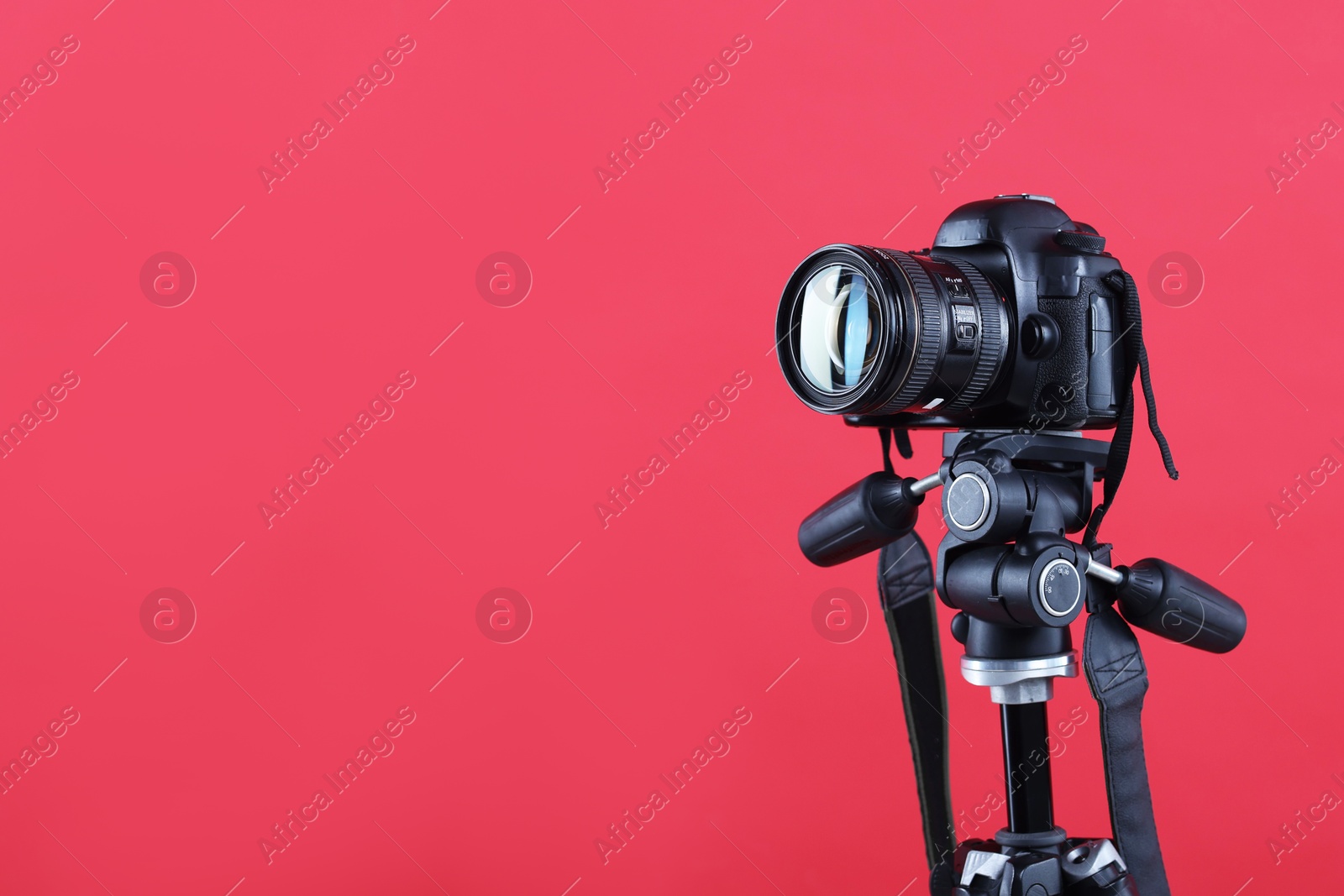 Modern professional video camera on red background, space for text Photo of Modern professional video camera on red background, space for text