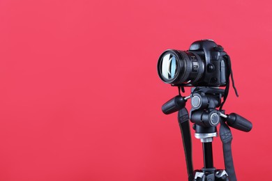Photo of Modern professional video camera on red background, space for text