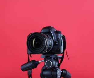 Photo of Modern professional video camera on red background, closeup
