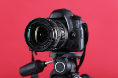 Photo of Modern professional video camera on red background, closeup