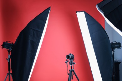 Photo of Modern video camera and professional lighting equipment on red background