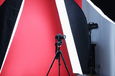 Photo of Modern video camera and professional lighting equipment on red background